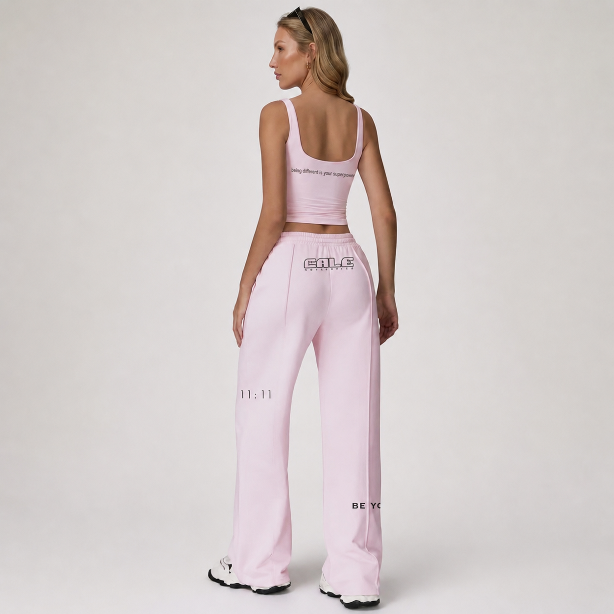 Light pink wide leg track pants with a relaxed fit, styled with a high waist and paired with a fitted top.
