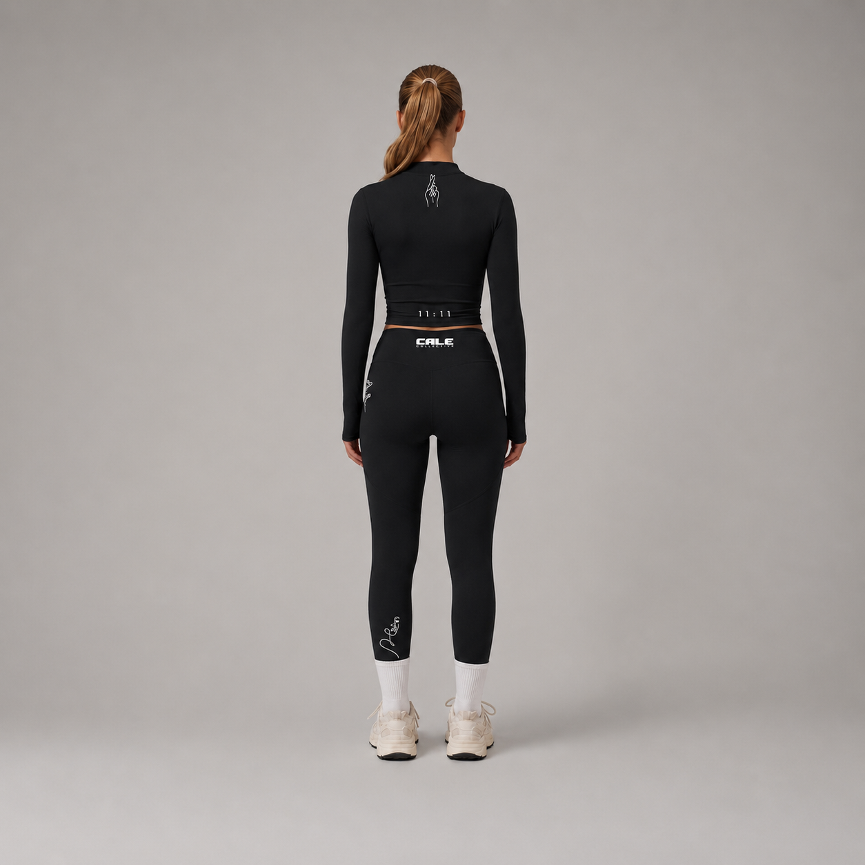 Black fitted long sleeve crop top worn with matching black leggings, showcasing a cropped length and fitted silhouette.