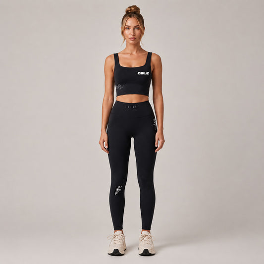 Black cropped sports bra with wide straps, styled with matching black leggings for a minimalistic look.