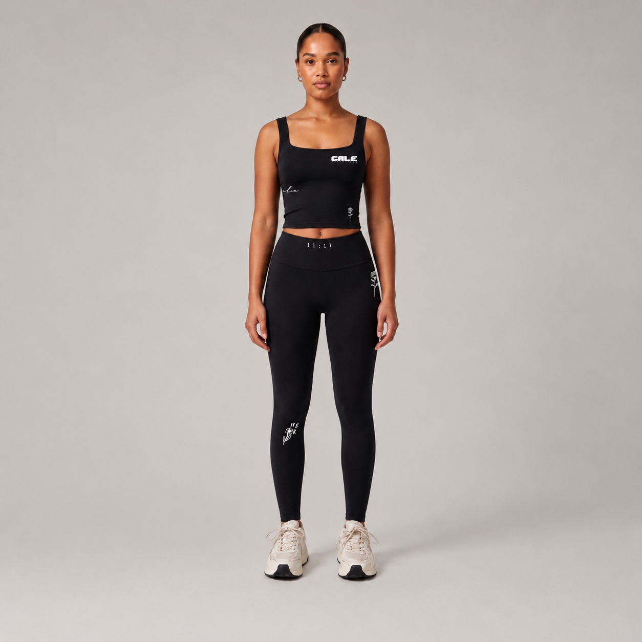 Black fitted tank top with square neckline worn by a model, paired with black leggings against a light background.