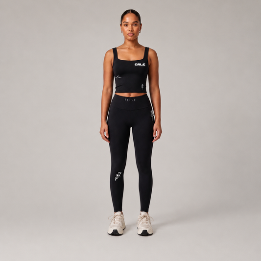 Black fitted tank top with square neckline worn by a model, paired with black leggings against a light background.