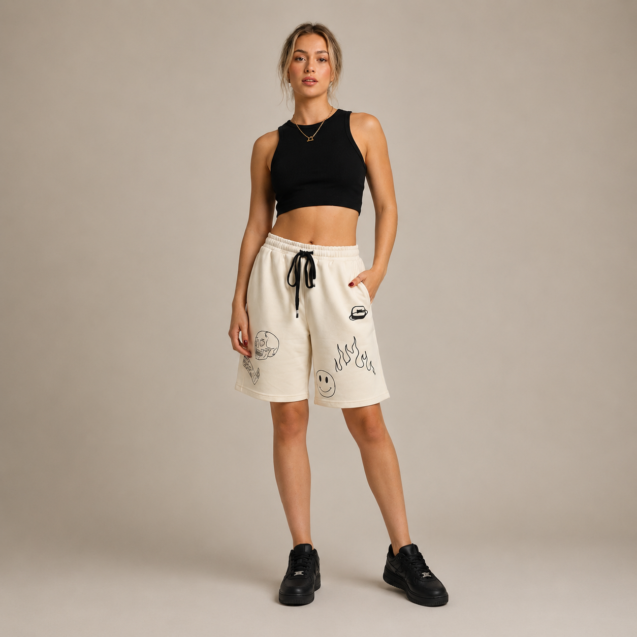 Light-coloured shorts with graphic designs, featuring an elastic waistband and drawcord, styled with a fitted black crop top.