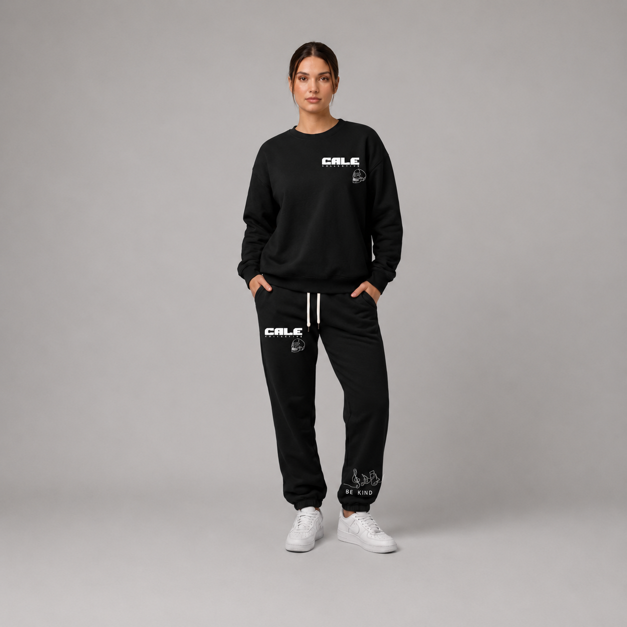 Model wearing a black oversized crew sweatshirt with streetwear-inspired graphics, styled with matching black pants and white sneakers.