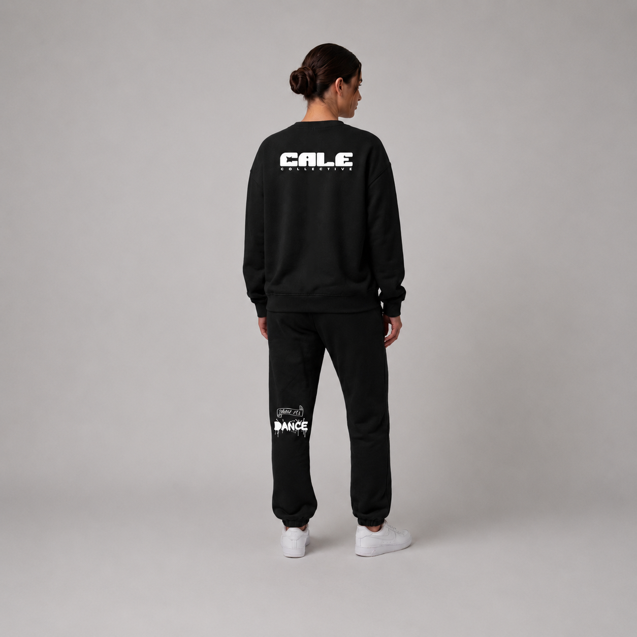 Black oversized crew sweatshirt with streetwear-inspired graphics, styled with matching black pants and white sneakers.