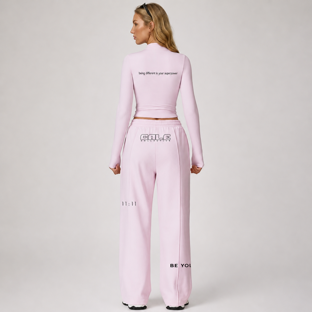 Pink fitted long sleeve crop top worn with matching pink pants, featuring a high neckline and back text detail.
