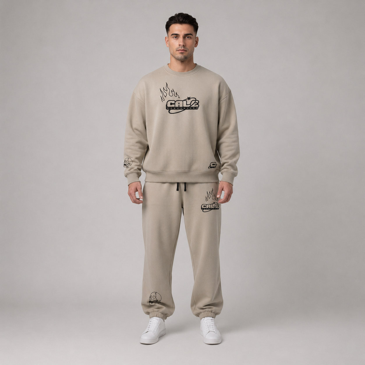 Model wearing a stone oversized crew sweatshirt with streetwear graphics, styled with matching pants and white sneakers.