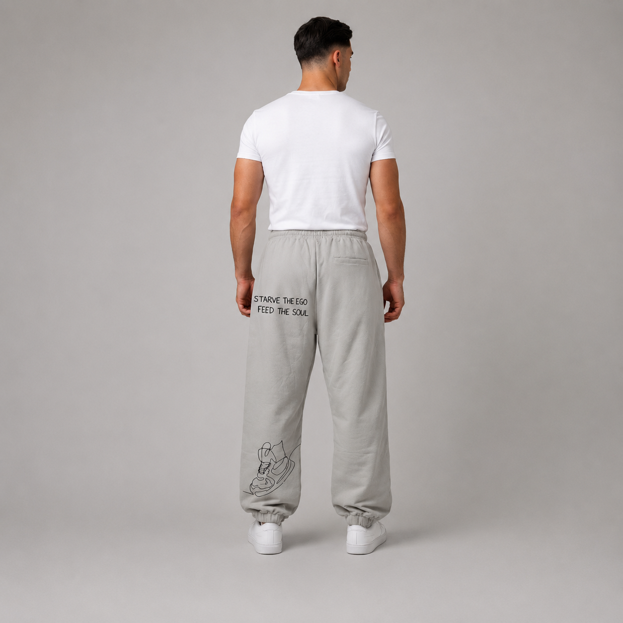 Light grey track pants with a relaxed fit, elastic waistband, drawcord, and graphic design on the back.