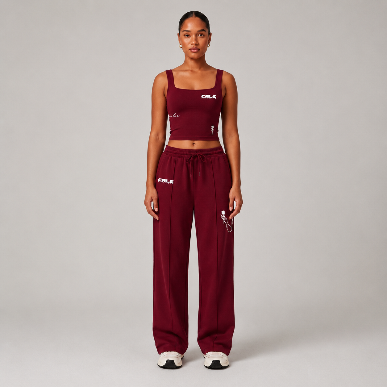 Woman wearing a burgundy fitted tank top with a square neckline and matching burgundy pants, showcasing minimal design.