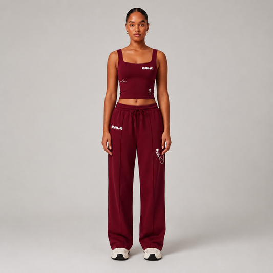 Woman wearing a burgundy fitted tank top with a square neckline and matching burgundy pants, showcasing minimal design.