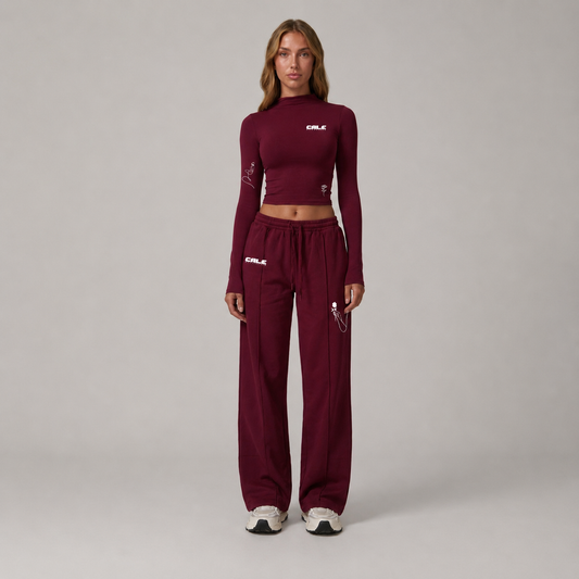 Model wearing a burgundy fitted long sleeve crop top with matching pants, styled for casual streetwear.