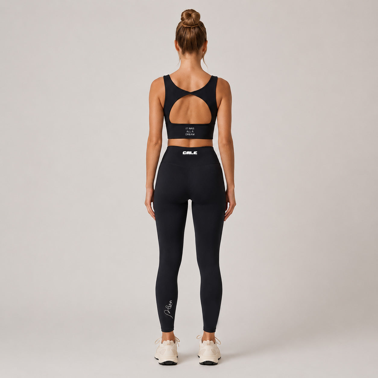 Black sports bra with scoop neckline and open back, styled with matching leggings for a minimalistic activewear look.
